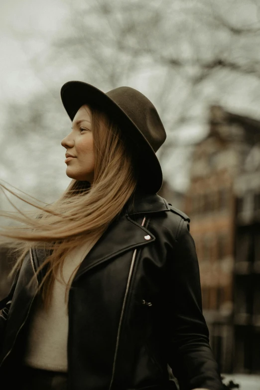 a woman with her hair blowing in the wind, pexels contest winner, renaissance, black stetson and coat, brown leather jacket, proud looking away, aurora aksnes