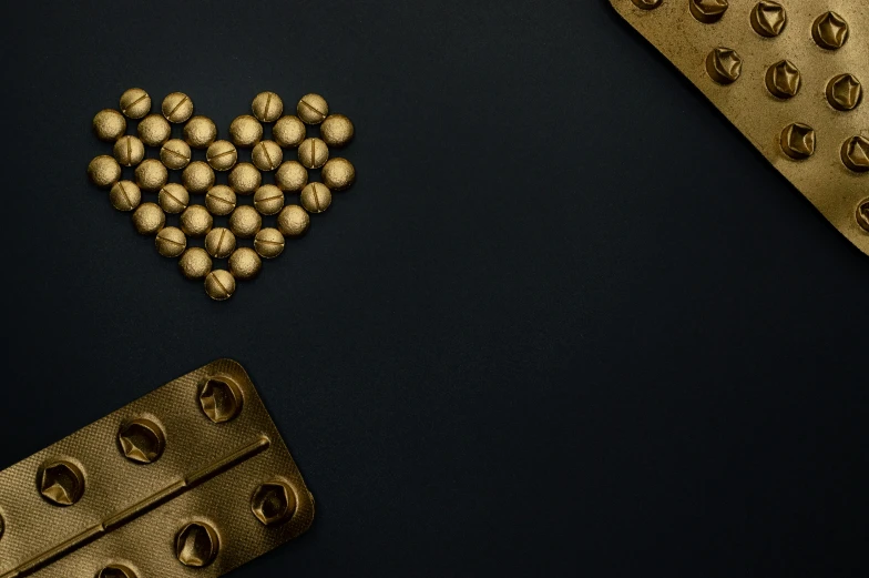 a couple of pills sitting on top of a table, black and gold palette, connected to heart machines, thumbnail, chocolate