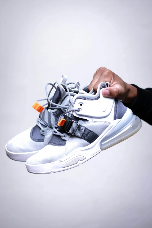 a person holding a pair of sneakers in their hand, an album cover, inspired by Jordan Grimmer, pexels contest winner, hypermodernism, orange grey white, straps, all white render, airforce gear