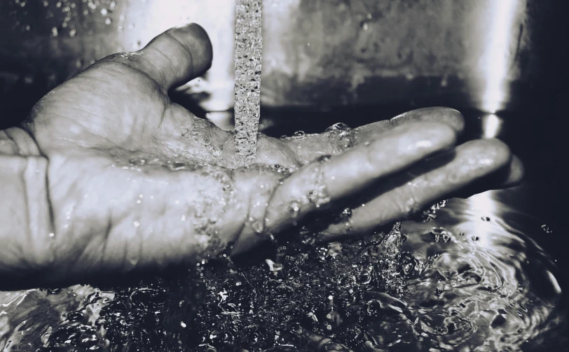 a person washing their hands with water from a faucet, a black and white photo, unsplash, process art, promo image, rivulets, 1900s photo, made of oil and water