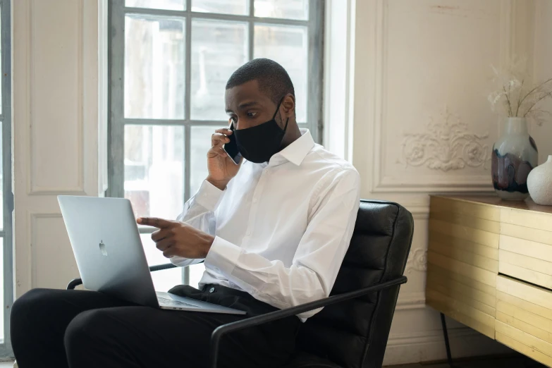 a man sitting in a chair talking on a cell phone, black facemask, using a macbook, henri moore, profile image