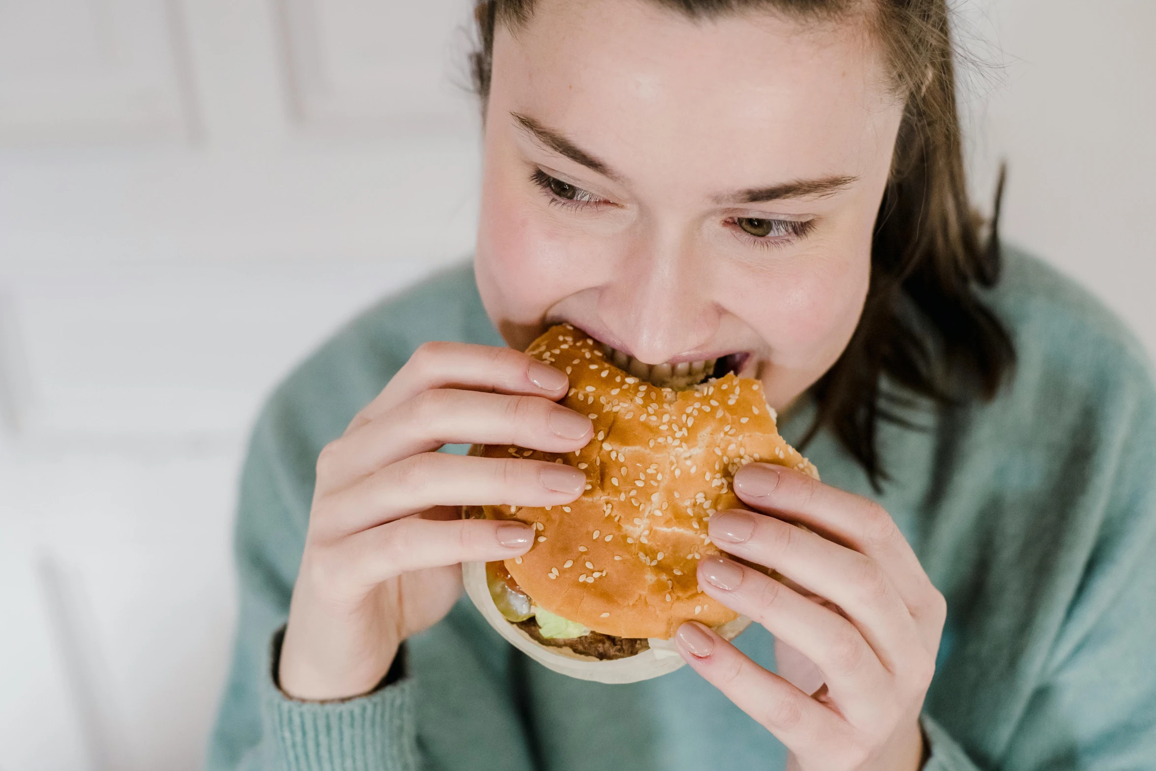 a close up of a person eating a hamburger, by Julia Pishtar, trending on pexels, fan favorite, épaule devant pose, gooey skin, background image