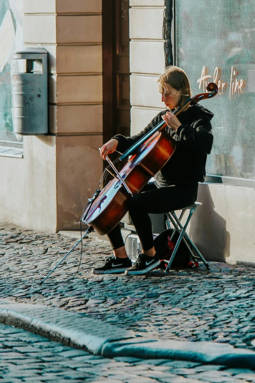 a man sitting on a chair playing a cello, pexels contest winner, in the middle of the street, photo of a woman, scandinavian, multiple stories