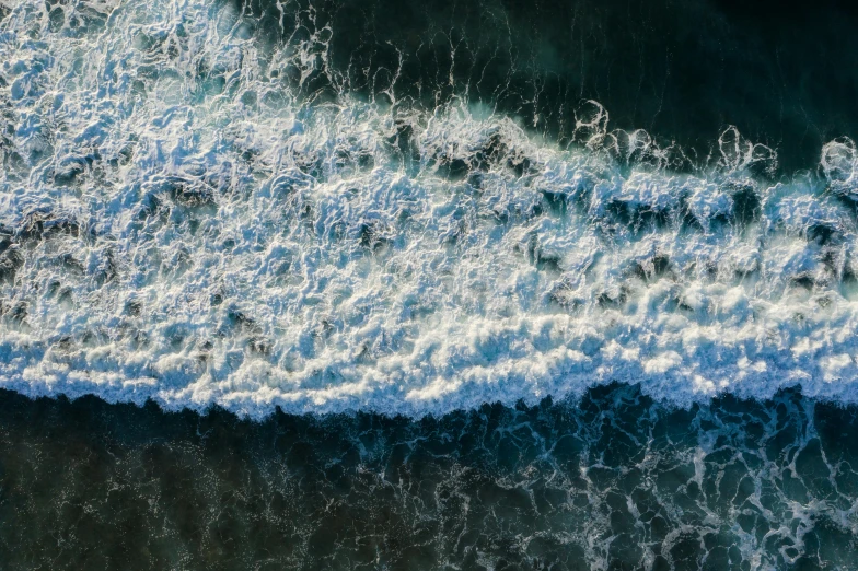 a person riding a surfboard on top of a wave, by Peter Churcher, pexels contest winner, renaissance, view from above on seascape, deep texture, sea foam, ocean caustics