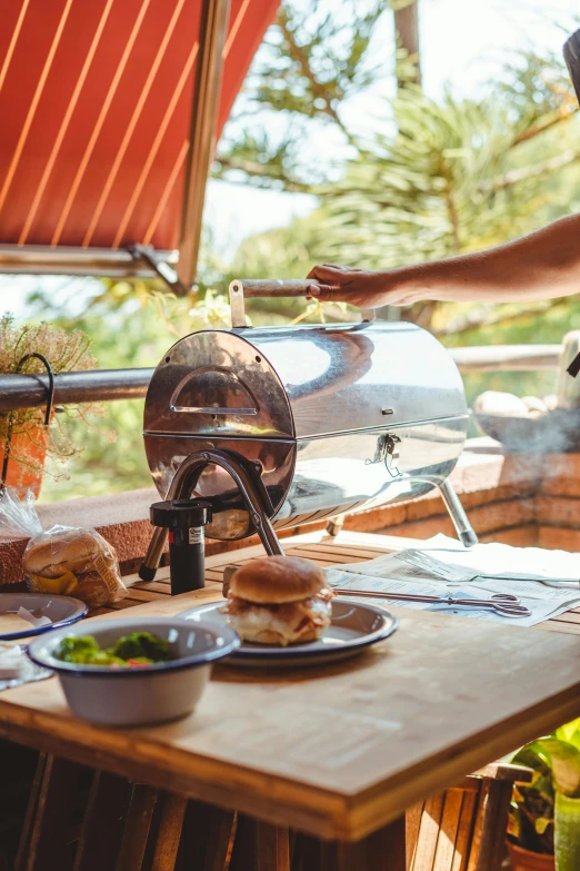 a man standing next to a table with food on it, barbecue, sparkling in the sunlight, operating on burgers, deck