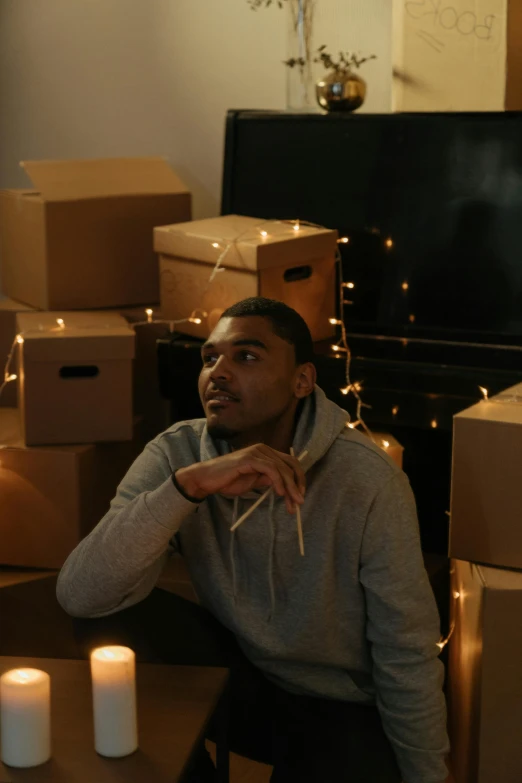 a man sitting in front of a pile of boxes, mkbhd, room full of candles, location in a apartment, college