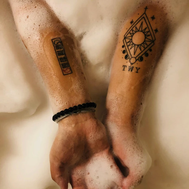 a close up of a person's hands with tattoos on them, a tattoo, bathtub, two suns, runic arm tattoos, set photo