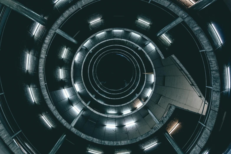 a spiral staircase in a building at night, an album cover, by Adam Marczyński, unsplash contest winner, bauhaus, symmetrical. sci - fi, open bank vault, camera looking down upon, unsplash 4k