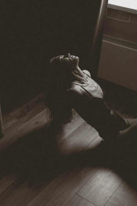 a black and white photo of a person laying on the floor, inspired by Elsa Bleda, unsplash, dark warm light, in ecstasy, standing in a dark, hair down to floor