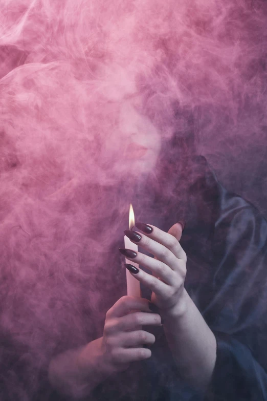 a woman holding a lit candle in her hands, an album cover, inspired by Elsa Bleda, trending on pexels, pink smoke, smoker, a seance, 2019 trending photo