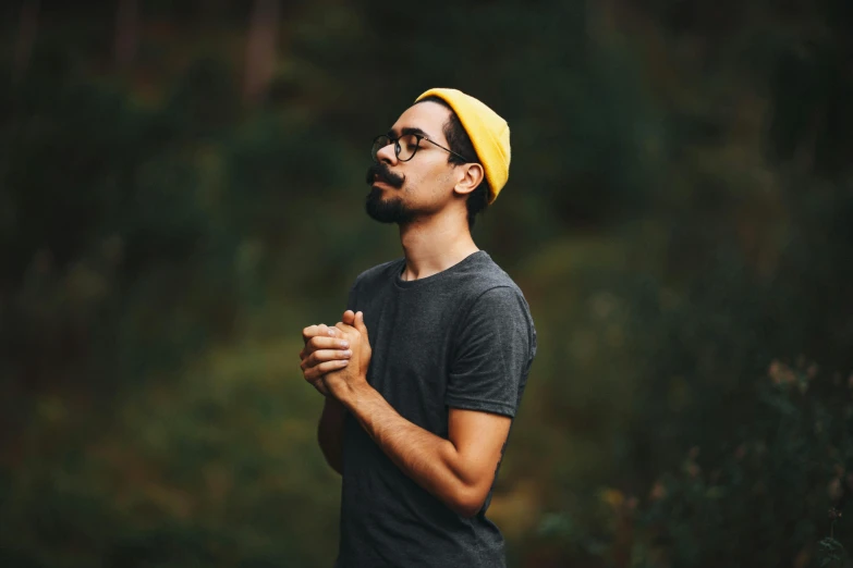 a man wearing a yellow hat and glasses, pexels contest winner, hurufiyya, praying posture, avatar image, aboriginal australian hipster, gentle calm doting pose