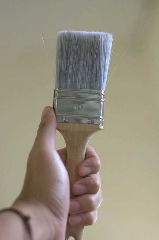a person holding a paint brush in their hand, up-close, shiny silver, caparisons, big brush