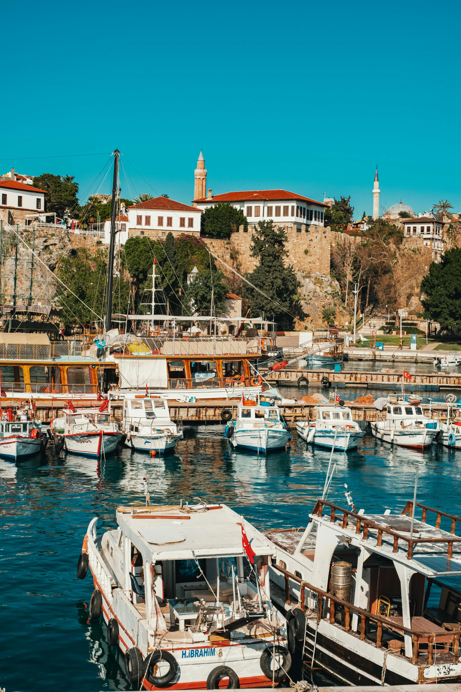 a harbor filled with lots of boats under a blue sky, a picture, renaissance, turkish and russian, cliffside town, 2022 photograph, white marble buildings