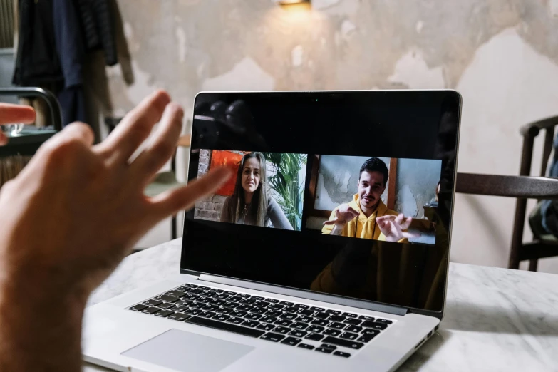 a laptop computer sitting on top of a table, by Julia Pishtar, pexels, video art, hand gestures, threes, teenager hangout spot, picture through the screen