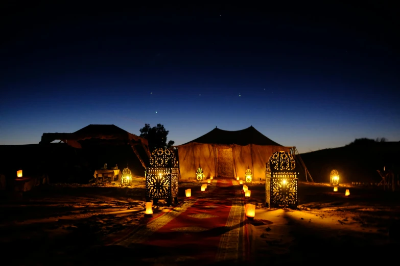 a tent set up in the desert at night, a mosaic, hurufiyya, floor lamps, ochre, gas lanterns, light tan