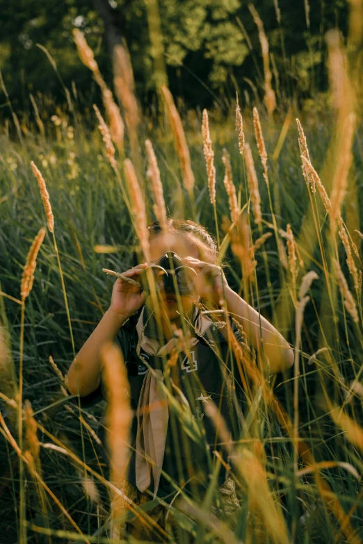 a woman taking a picture in a field of tall grass, a picture, inspired by Elsa Bleda, unsplash contest winner, childish look, spying, head shot, hunting