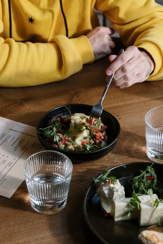 a person sitting at a table with a plate of food, by Jan Tengnagel, trending on unsplash, bowl, humus, plated arm, casually dressed