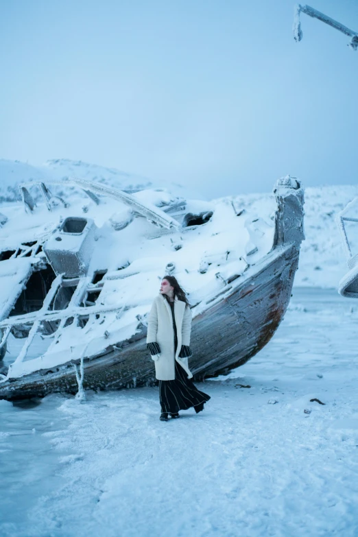 a woman standing in front of a boat in the snow, an album cover, pexels contest winner, shipwreck, nordic pastel colors, actress, black