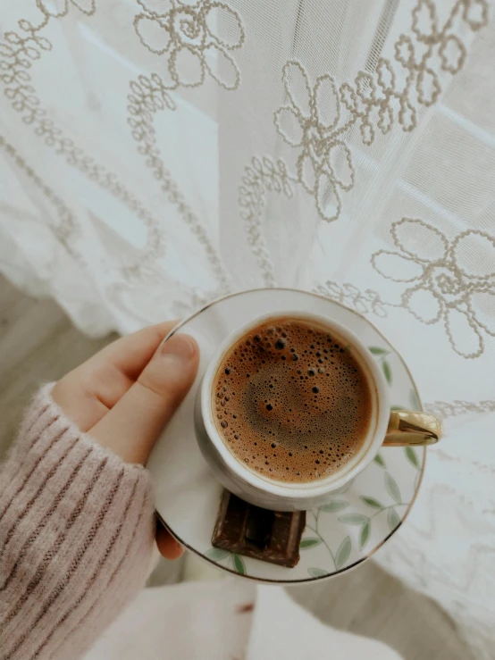 a close up of a person holding a cup of coffee, by Lucia Peka, trending on pexels, romanticism, embroidered velvet, islamic, gif, brown:-2