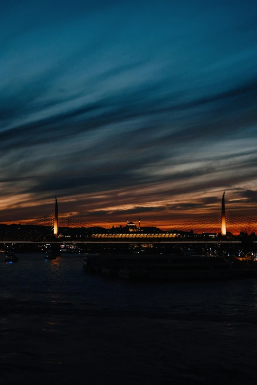 a boat floating on top of a body of water, during the night, bridge, at the golden hour, wide views