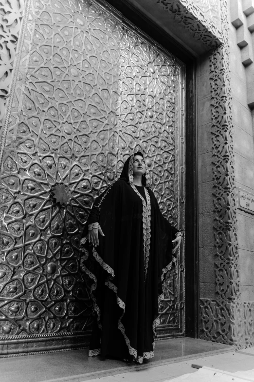 a black and white photo of a woman standing in front of a door, an album cover, inspired by Osman Hamdi Bey, flickr, arabesque, ffffound, mausoleum, papa emeritus, ezra stoller