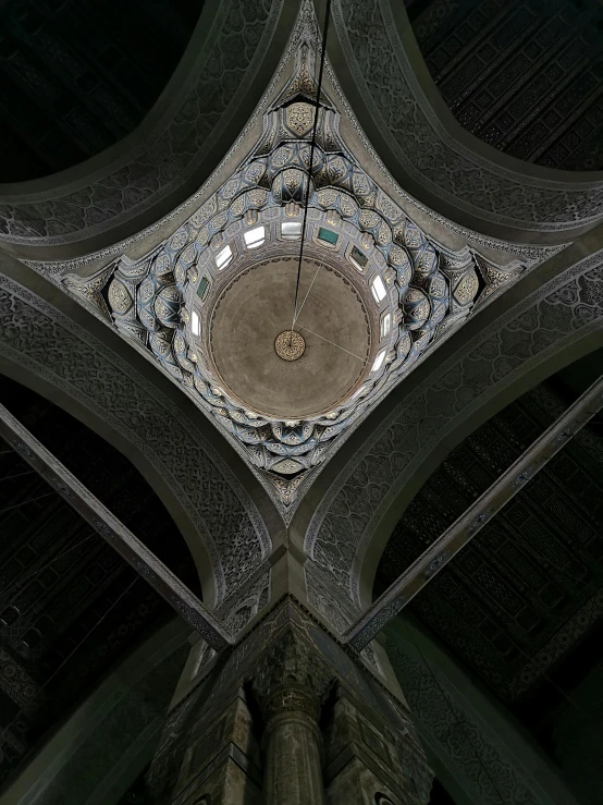 a clock hanging from the ceiling of a building, by Ahmed Yacoubi, arabesque, helmet view, ceiling hides in the dark, lead - covered spire, ((fish eye))