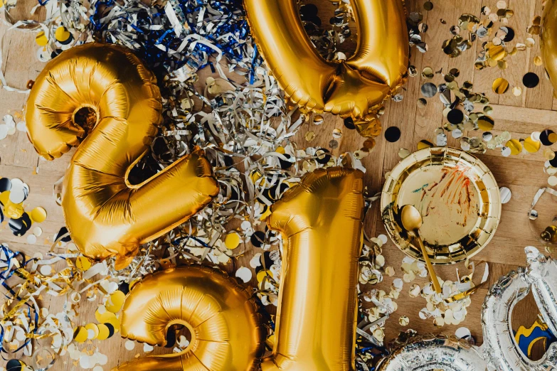 a table topped with gold balloons and confetti, by Julia Pishtar, trending on unsplash, 1970s photo, background image, miscellaneous objects, 1990's photo