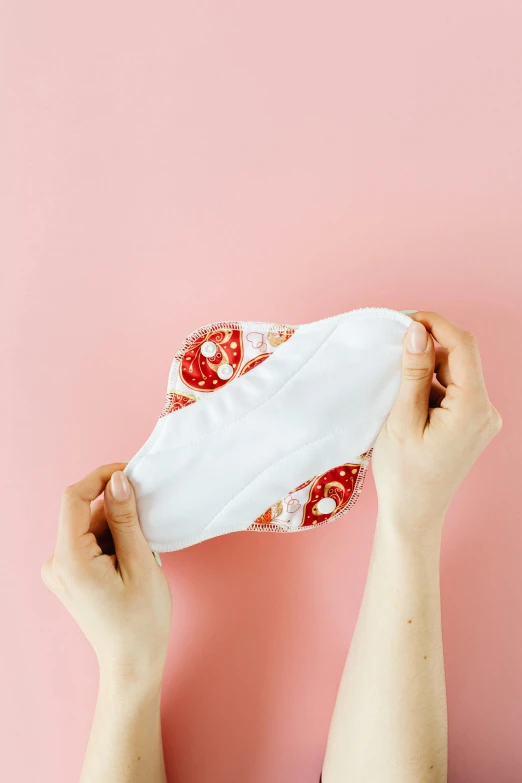 a person holding a piece of cloth over their face, soft pads, red and white color theme, bralette, detailed product image