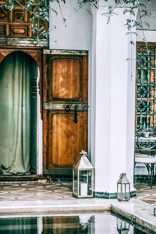 a large wooden door sitting next to a pool, arabesque, stately robes, lanterns, 1 9 2 0 s room, oud