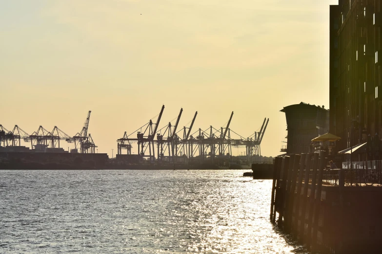 a large body of water surrounded by tall buildings, by Carey Morris, pexels contest winner, shipping docks, silhouetted, cranes, coastal