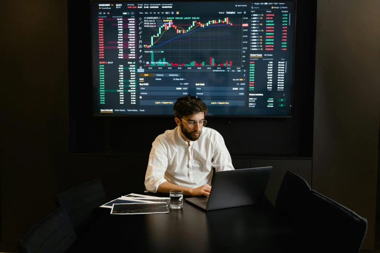 a man sitting at a table with a laptop in front of him, by Adam Marczyński, pexels, analytical art, displaying stock charts, australian, inside an epic, avatar image