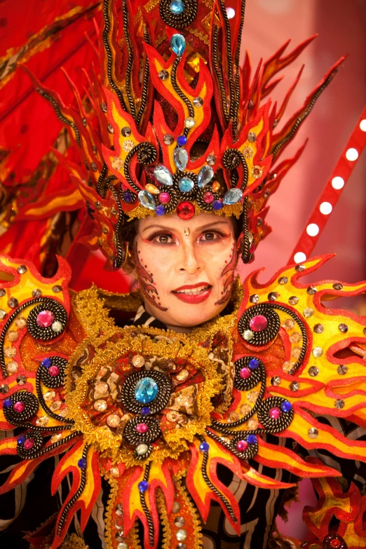 a close up of a person wearing a costume, by Gwen Barnard, philippines, dazzling lights, red and orange glow, taiwan