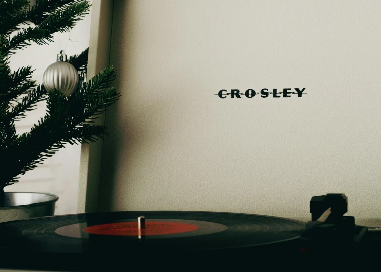 a record player sitting next to a christmas tree, an album cover, inspired by William Crozier, pexels, vintage typography, chesley, close body shot, glossy white