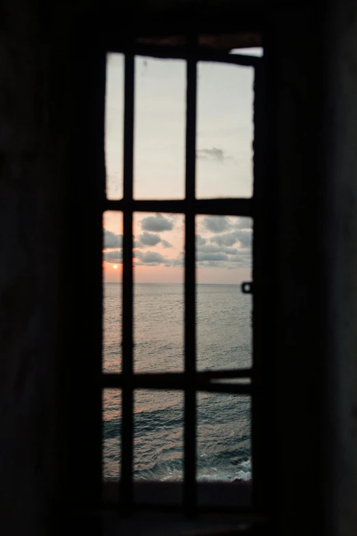 a window with a view of the ocean, by Alessandro Allori, unsplash, romanticism, medium format. soft light, prison cell, sunset photo, tall