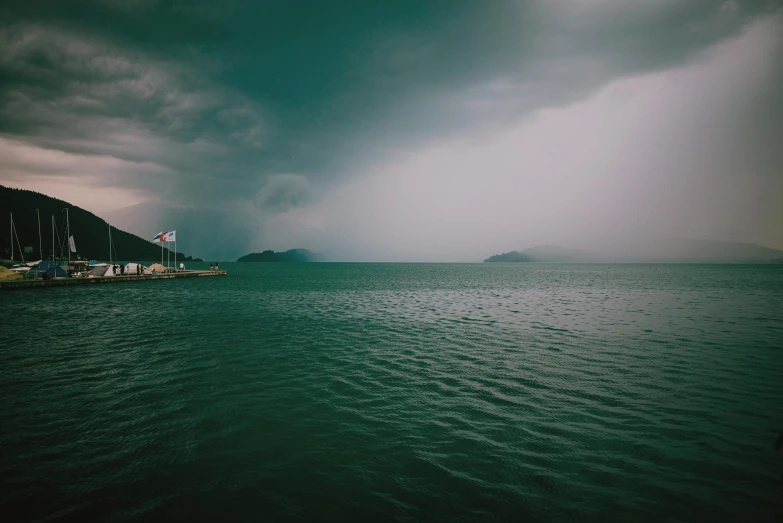 a group of boats sitting on top of a body of water, a picture, unsplash contest winner, romanticism, thunderstorm, dark green water, harbor, low quality photo