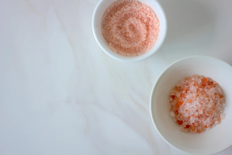 a close up of two bowls of food on a table, inspired by Gentile Bellini, trending on unsplash, close up of single sugar crystal, pale red, skincare, slush