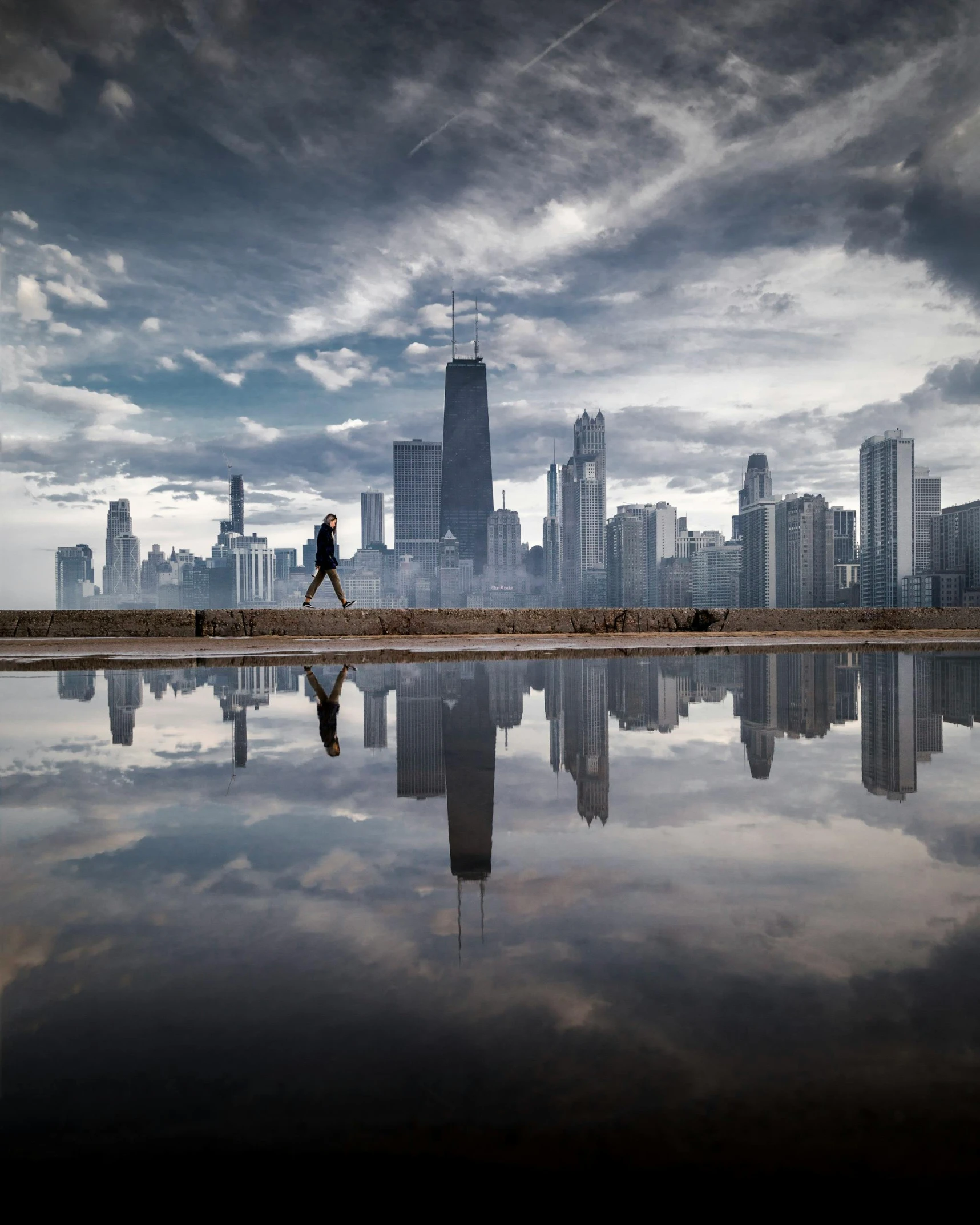 a person walking in front of a body of water with a city in the background, by Erik Pevernagie, art photography, chicago, skies, viral image, 5 0 0 px