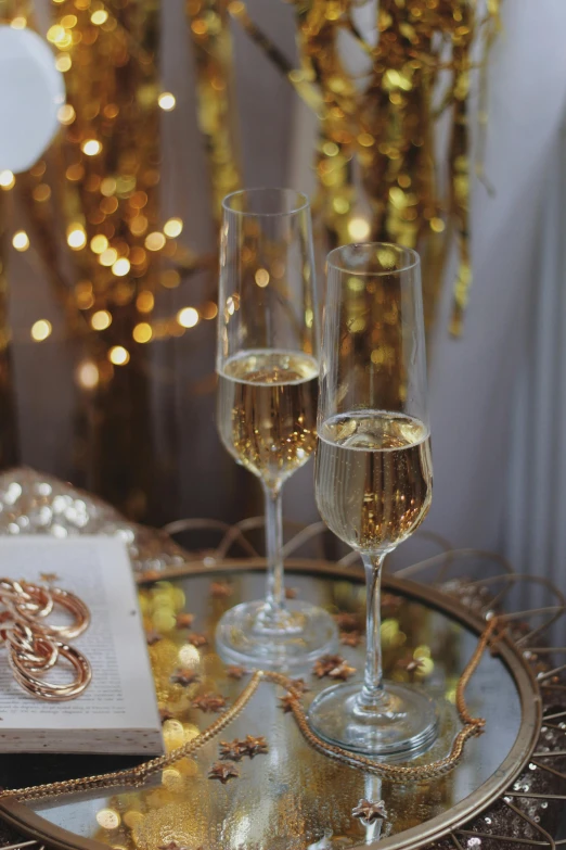 a couple of wine glasses sitting on top of a table, gold jewellery, bubbly, decorations, wearing gold glasses