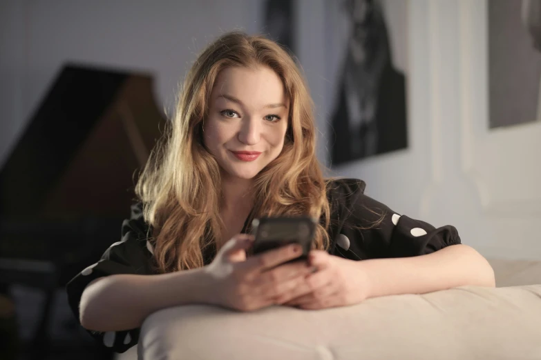 a woman sitting on a couch holding a cell phone, a portrait, by David Donaldson, shutterstock, renaissance, portrait of teenage emma stone, sydney sweeney, 15081959 21121991 01012000 4k, taken with canon 5d mk4