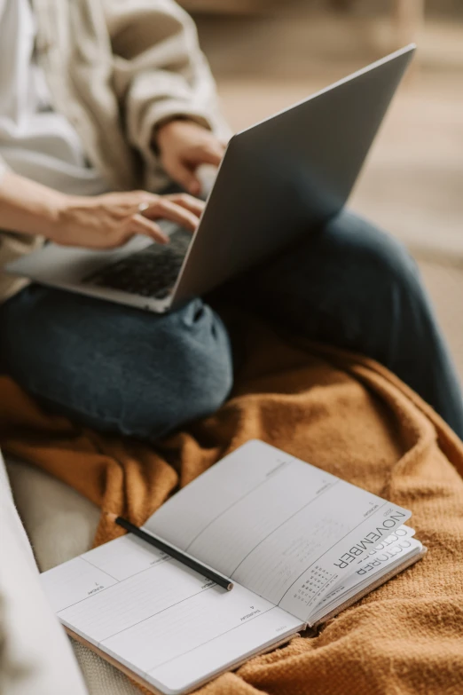 a woman sitting on a couch using a laptop, trending on pexels, lined paper, with two front pockets, rounded lines, historical image