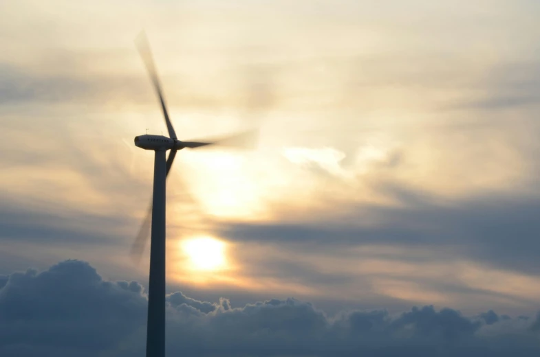 a wind turbine with the sun setting behind it, by Carey Morris, pexels contest winner, dynamic closeup, avatar image, thumbnail, slight haze