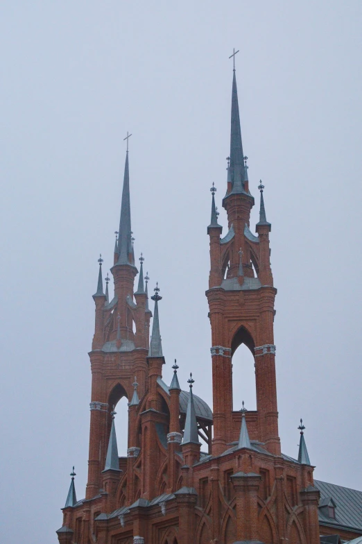 a large red brick building with two spires, inspired by Gyula Aggházy, foggy!, tula, up-close, majestic spires