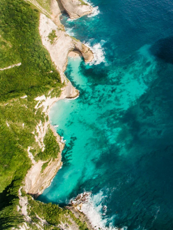 a large body of water next to a lush green hillside, pexels contest winner, carribean turquoise water, drone photograph, light and dark, over a chalk cliff