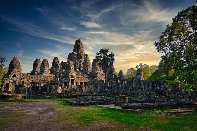 a large stone building surrounded by trees, unsplash contest winner, angkor thon, vivid sky, tall stone spires, 8k resolution”