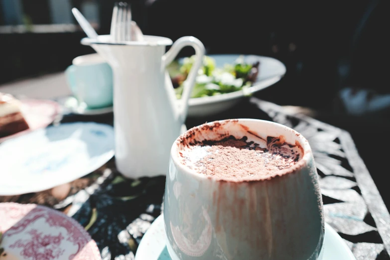 a cup of hot chocolate sitting on top of a table, unsplash, eating outside, in a red dish, background image, closeup at the food