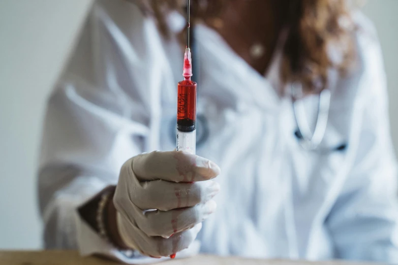 a woman in a lab coat is holding a syll, by Julia Pishtar, pexels contest winner, syringe, red liquid, spear in hand, brown