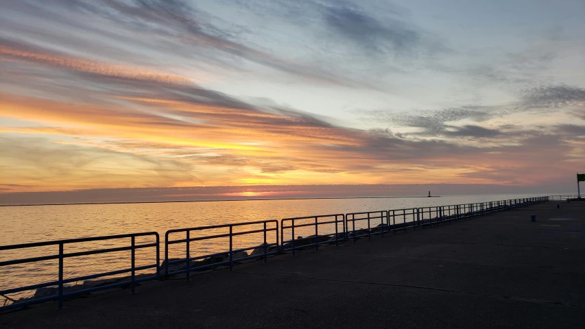 a bench sitting on top of a pier next to a body of water, happening, at the sunset, cleveland, seaview, listing image