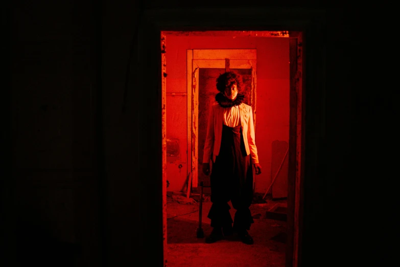 a woman standing in a doorway in a dark room, orange and red lighting, horror themed, a person standing in front of a, production photo