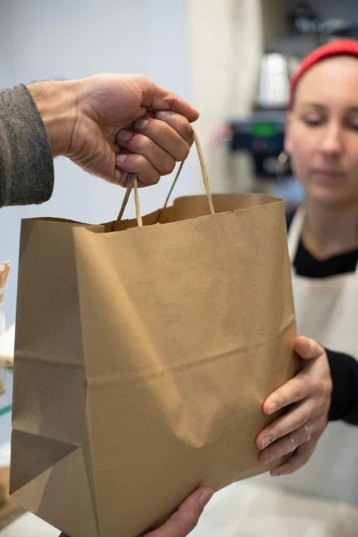 a person handing a bag of food to another person, brown paper, square, thumbnail, store