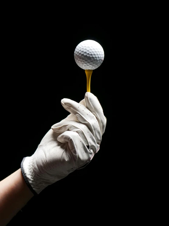 a gloved hand holding a golf ball on a tee, by Matthias Stom, unsplash, hyperrealism, gold paint, performance, ilustration, tastes